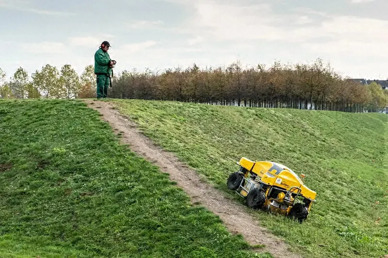 Remote-controlled mower cutting grass on a steep grassy slope